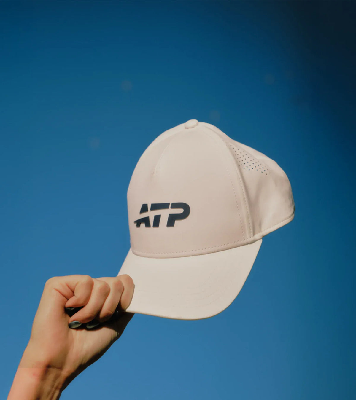 White cap with ATP logo held against a blue sky