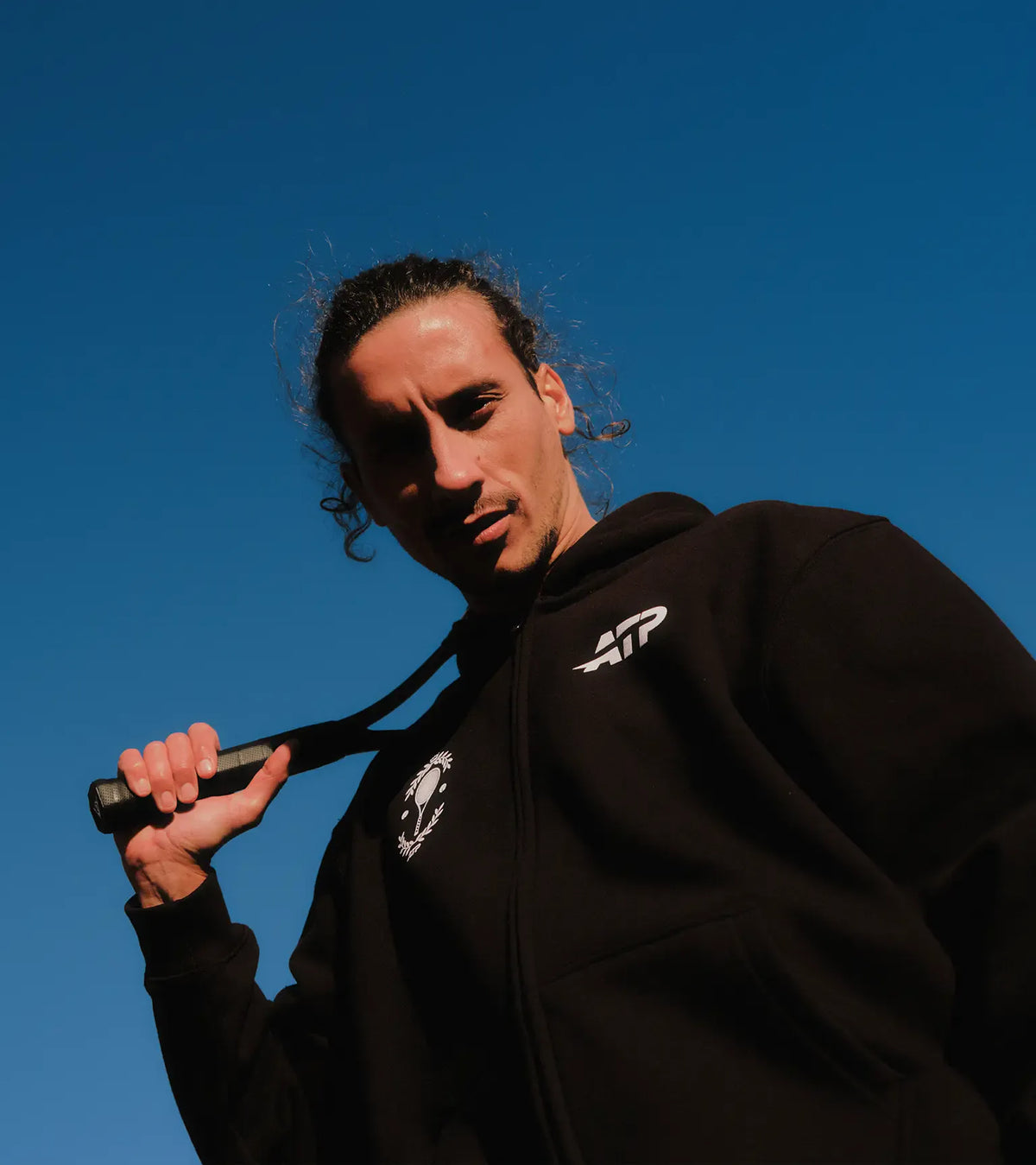 Man wearing a black ATP hoodie against a clear blue sky