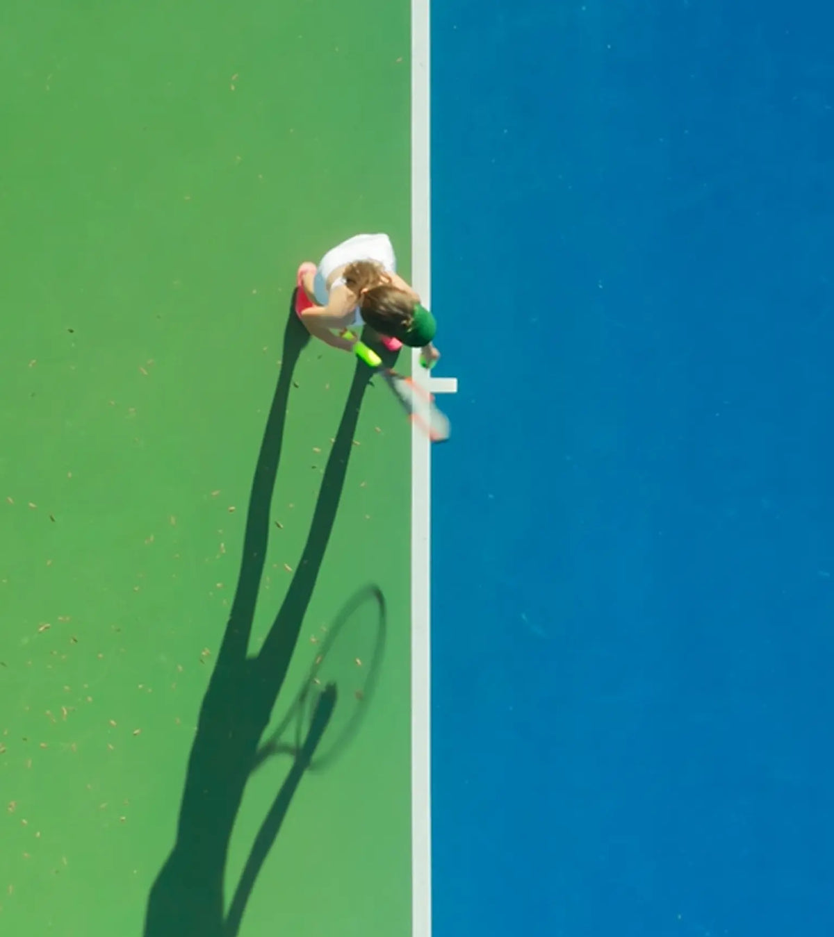 Person playing on a tennis court, viewed from above.